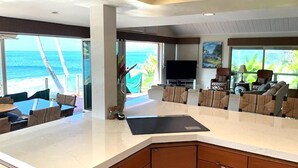 Una cuina moderna amb una illa gran, una zona de menjador amb vista a l'oceà i una sala d'estar amb seients còmodes.
