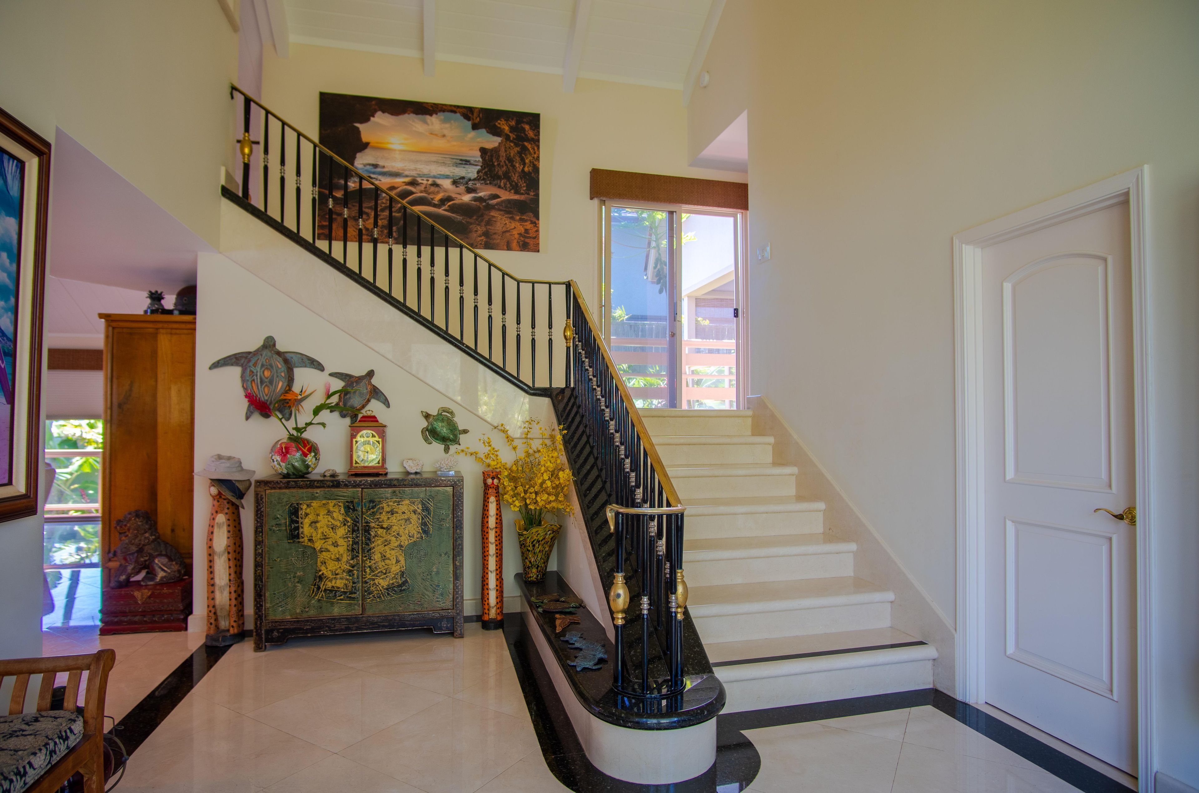 A staircase with a black railing, a painting above, and a door to the right.
