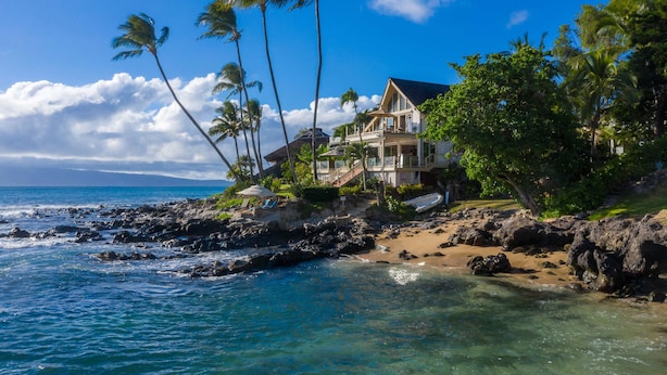 A beachfront property with a large house, a rocky shoreline, and palm trees. - 3br/3.5ba Oceanfront home with pool and hot tub! (Lahaina)