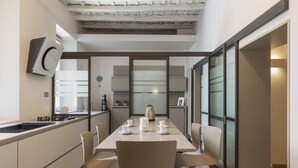 Una cocina moderna con una mesa de comedor preparada para cuatro personas, una cafetera y un horno empotrado.