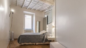Un dormitorio con cama, mesita de noche, espejo y radiador.