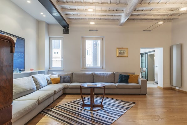 A living room with a sectional sofa, a round coffee table, and a striped rug.