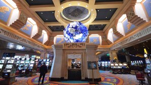 A casino interior with slot machines, a large decorative globe, and ornate ceiling designs.
