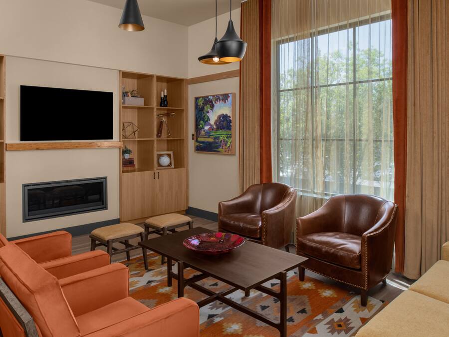 Una sala de estar con televisión de pantalla plana, sillones de cuero, una mesa de centro y una chimenea.