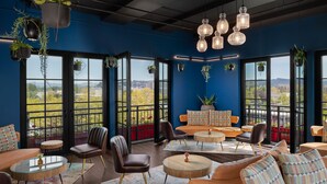 A modern lounge area with seating, tables, and hanging plants. - The Gordon Hotel (Eugene)