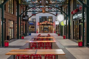 Un vestíbulo de hotel con un amplio espacio de estar abierto, una cafetería y un restaurante a la vista.
