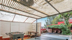 A covered outdoor area with a foosball table, ping pong table, and seating. - Mountain Chalet with Sea Views & Pool (Moya)