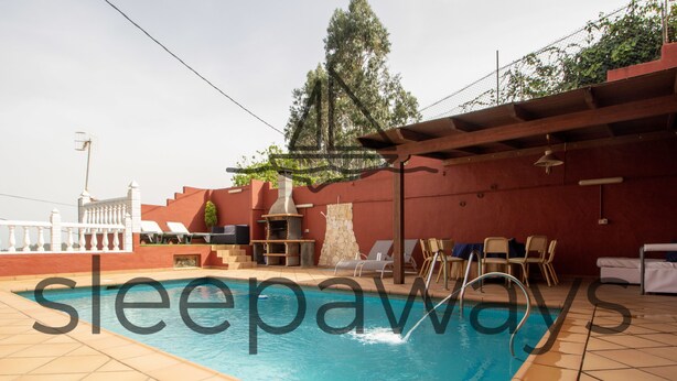 A swimming pool with a stone-tiled deck, lounge chairs, and a barbecue area. - Mountain Chalet with Sea Views & Pool (Moya)