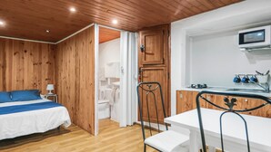 A room with a bed, a desk, a chair, and a kitchenette. - Mountain Chalet with Sea Views & Pool (Moya)
