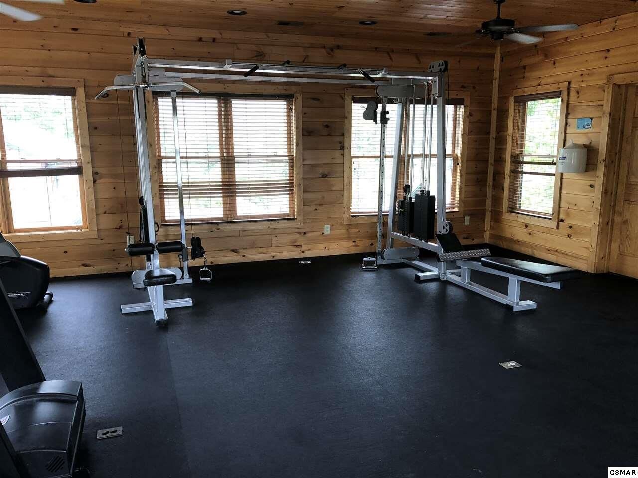 A gym with exercise equipment, large windows, and a black floor.
