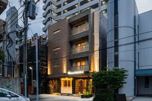 Un edificio de varios pisos con fachada moderna, que destaca por una entrada iluminada con señalización.