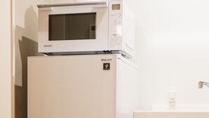 Una kitchenette compacta con un refrigerador de doble puerta, un microondas y un armario de madera.