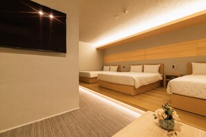 A modern hotel room with two single beds, a flat-screen TV mounted on the wall, and a small table with a vase of flowers. - Grand Base Hakata Station (Fukuoka)