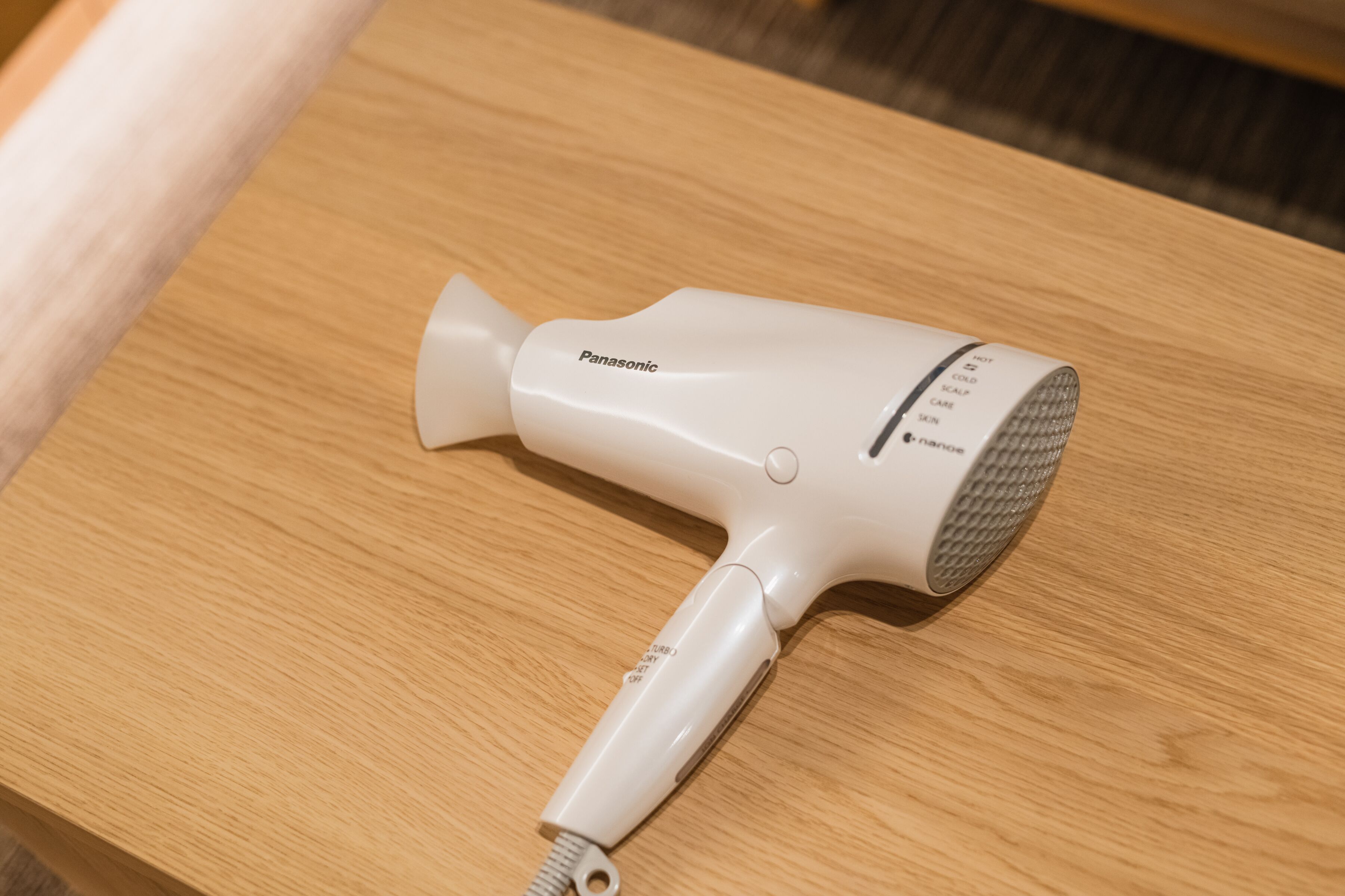 A Panasonic hair dryer on a wooden table.