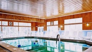 Ein Poolbereich mit Holzboden, großen Glaswänden und Fliesenböden.