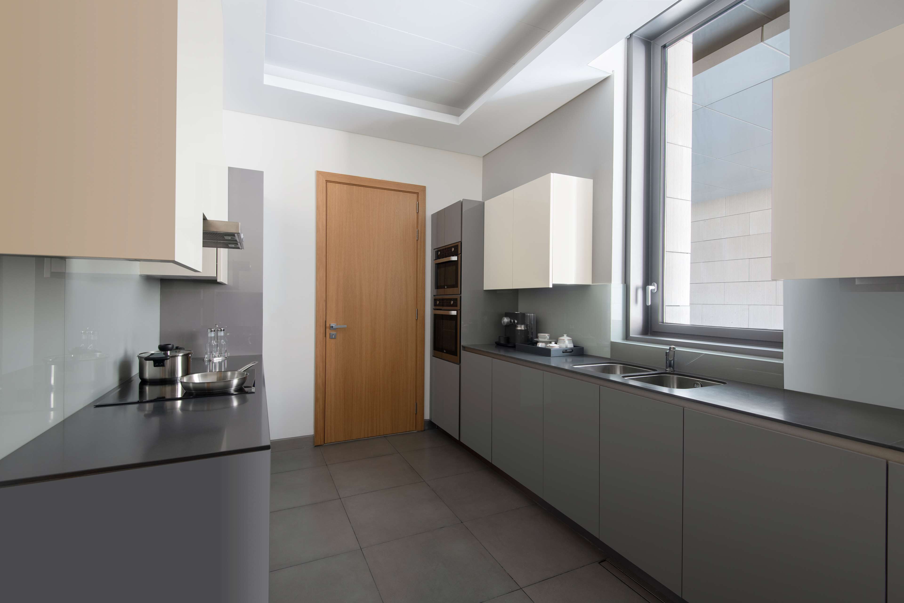 A modern kitchen with a built-in oven, a coffee machine, and a window providing natural light.