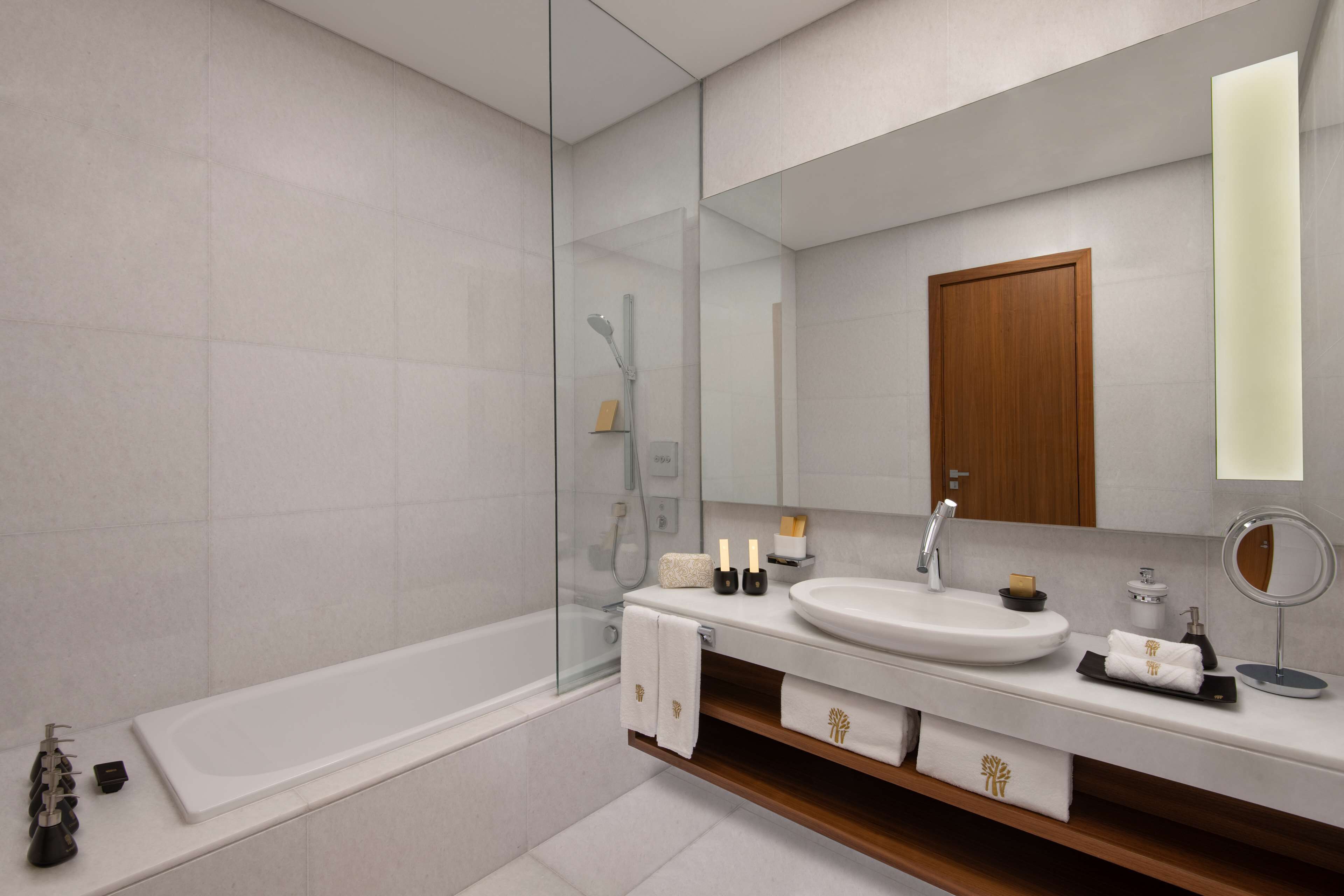 A modern bathroom with a glass-enclosed shower, a white sink, and a wooden vanity.