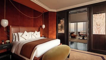 Una habitación de hotel moderna con una cama grande, un área de descanso con vistas y un ventanal amplio.