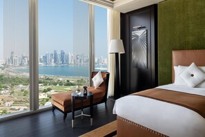 A hotel room with a large window, a bed, a chair, a table, and a lamp. - Banyan Tree Doha at La Cigale Mushaireb (Doha)
