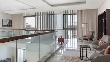 A modern living room with a glass railing, a sofa, a coffee table, and a view of the city.