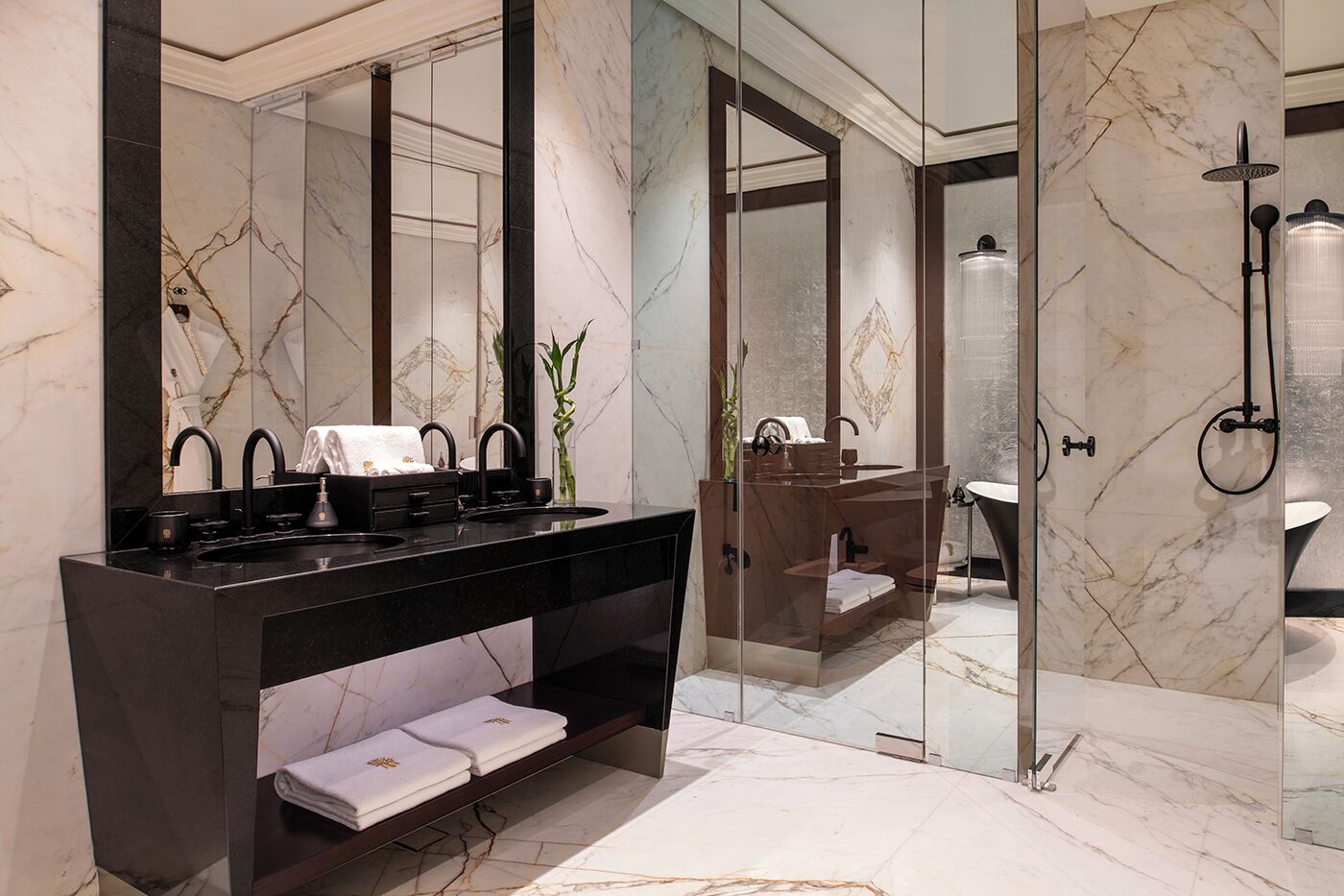 Une salle de bain moderne avec un meuble-lavabo noir, une douche en verre et un sol en marbre.