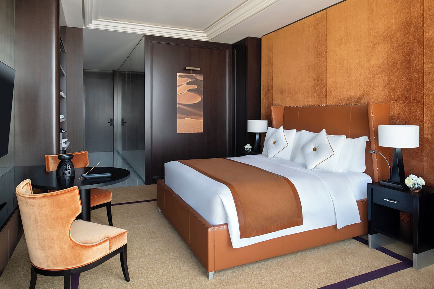 Une chambre d’hôtel moderne avec un grand lit, un bureau avec une chaise, une table de chevet et un miroir.