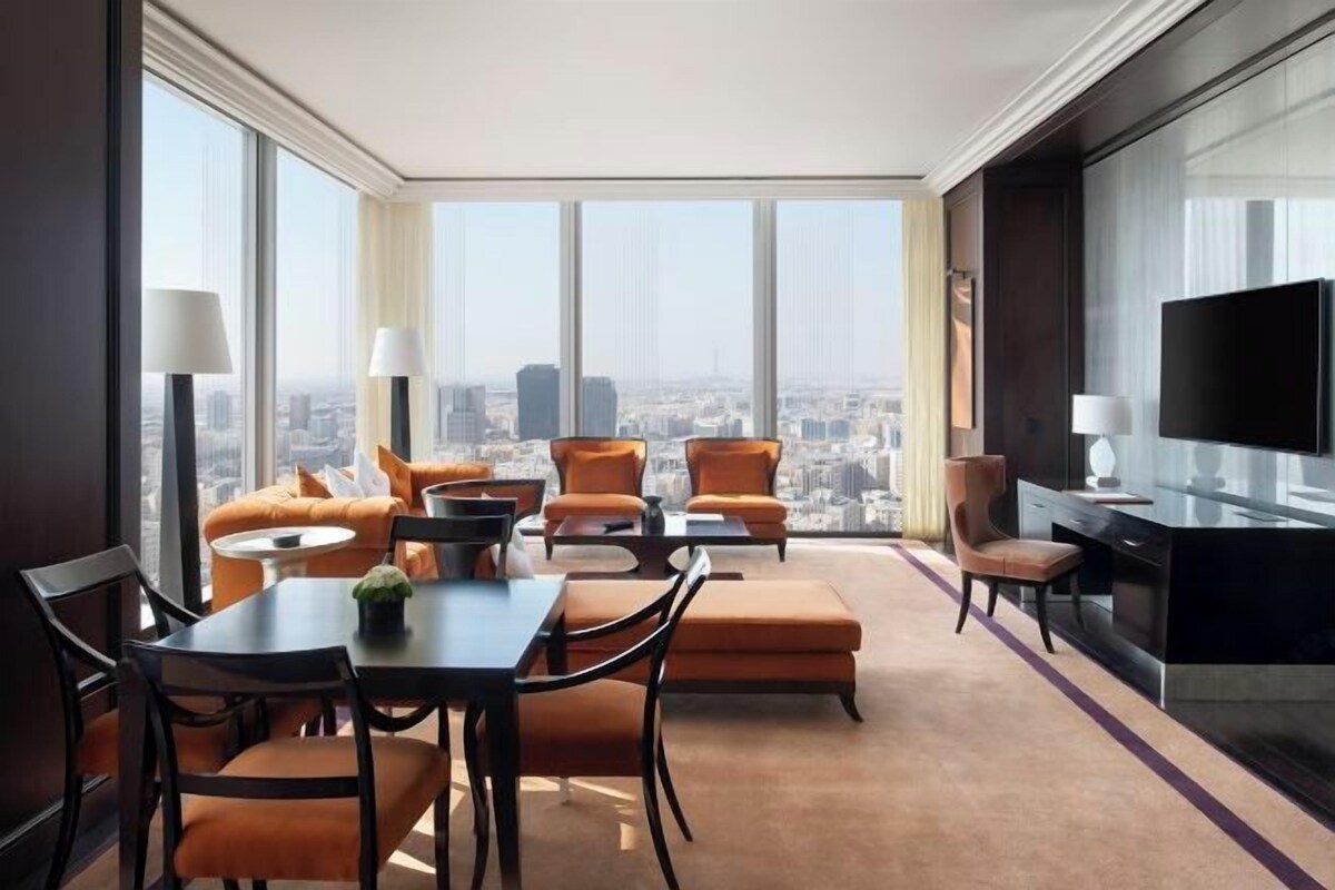Una habitación de hotel moderna con vistas a la ciudad, un área de comedor y un televisor.