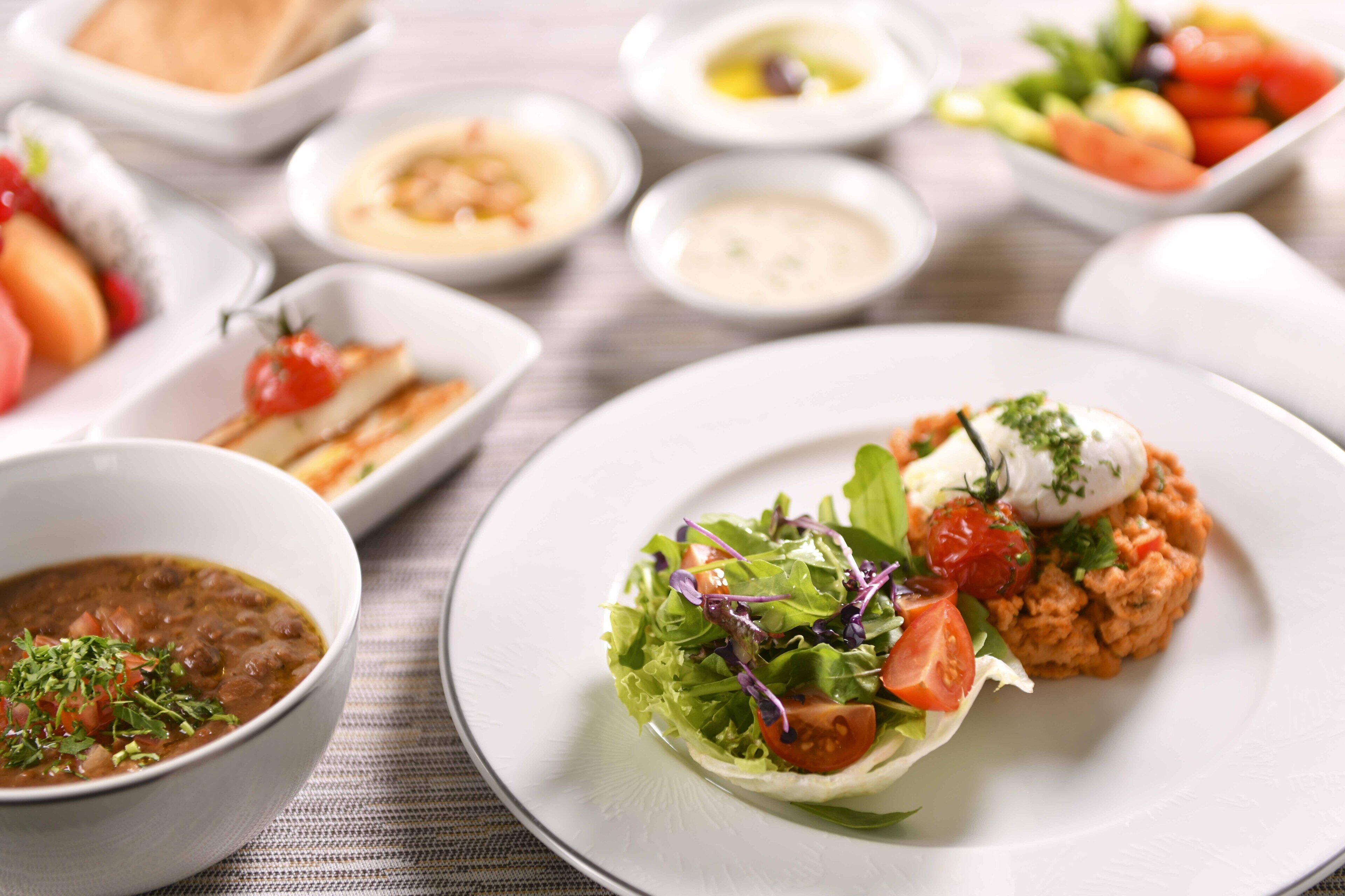 Un assortiment de plats comprenant une salade avec un œuf poché, une soupe et plusieurs petites assiettes avec différents mets.