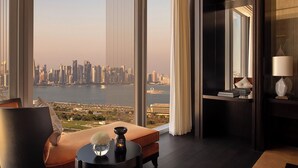 A modern hotel room with a large window offering a city view, a comfortable seating area, and a small table with decorative items. - Banyan Tree Doha at La Cigale Mushaireb (Doha)