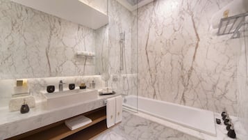 A modern bathroom with a marble backsplash, a large mirror, a double sink vanity, a bathtub, and a shower area.