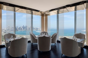 A dining area with a cityscape view, featuring a table set for two with chairs. - Banyan Tree Doha at La Cigale Mushaireb (Doha)