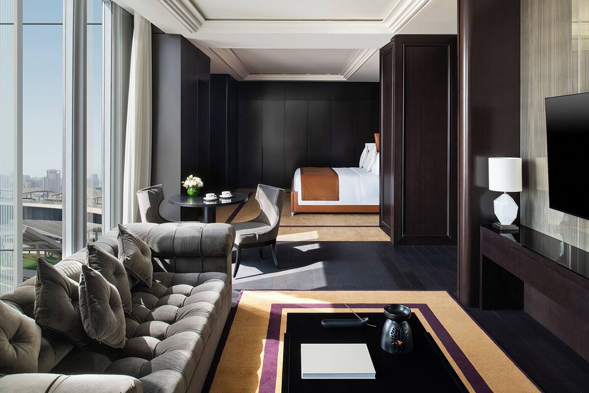 Una habitación de hotel moderna con sofá, cama, televisión y vistas a la ciudad.