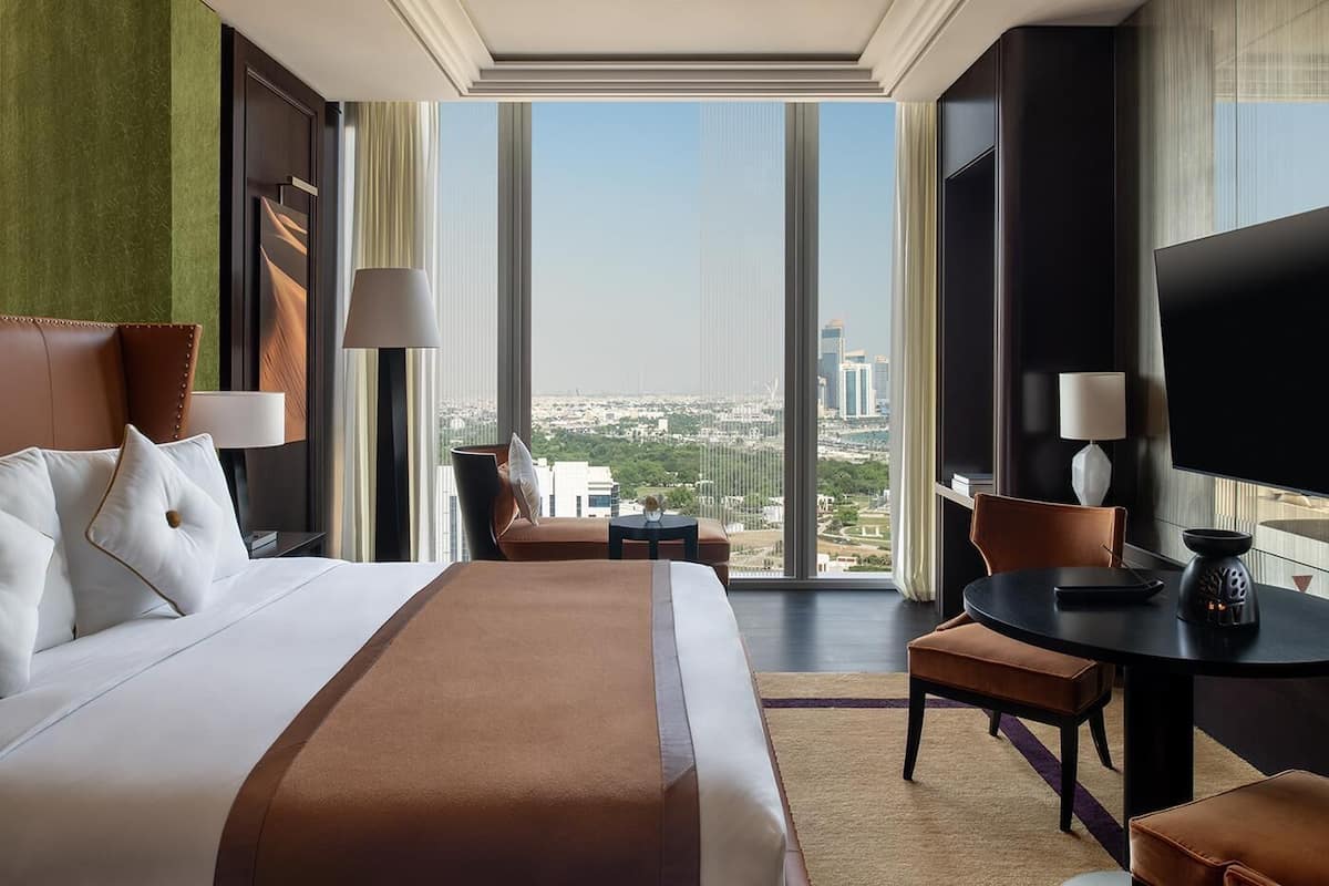 Ein Hotelzimmer mit einem großen Bett, einem Schreibtisch, einem Stuhl und Blick auf die Stadt.