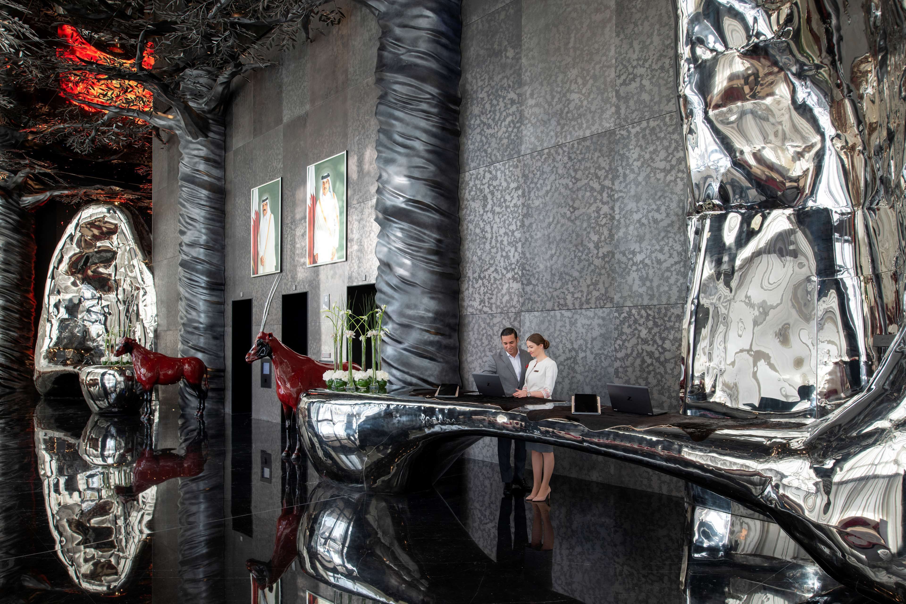 A modern lobby with reflective surfaces and a central sculpture.