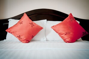 A bed with two red pillows and white sheets.