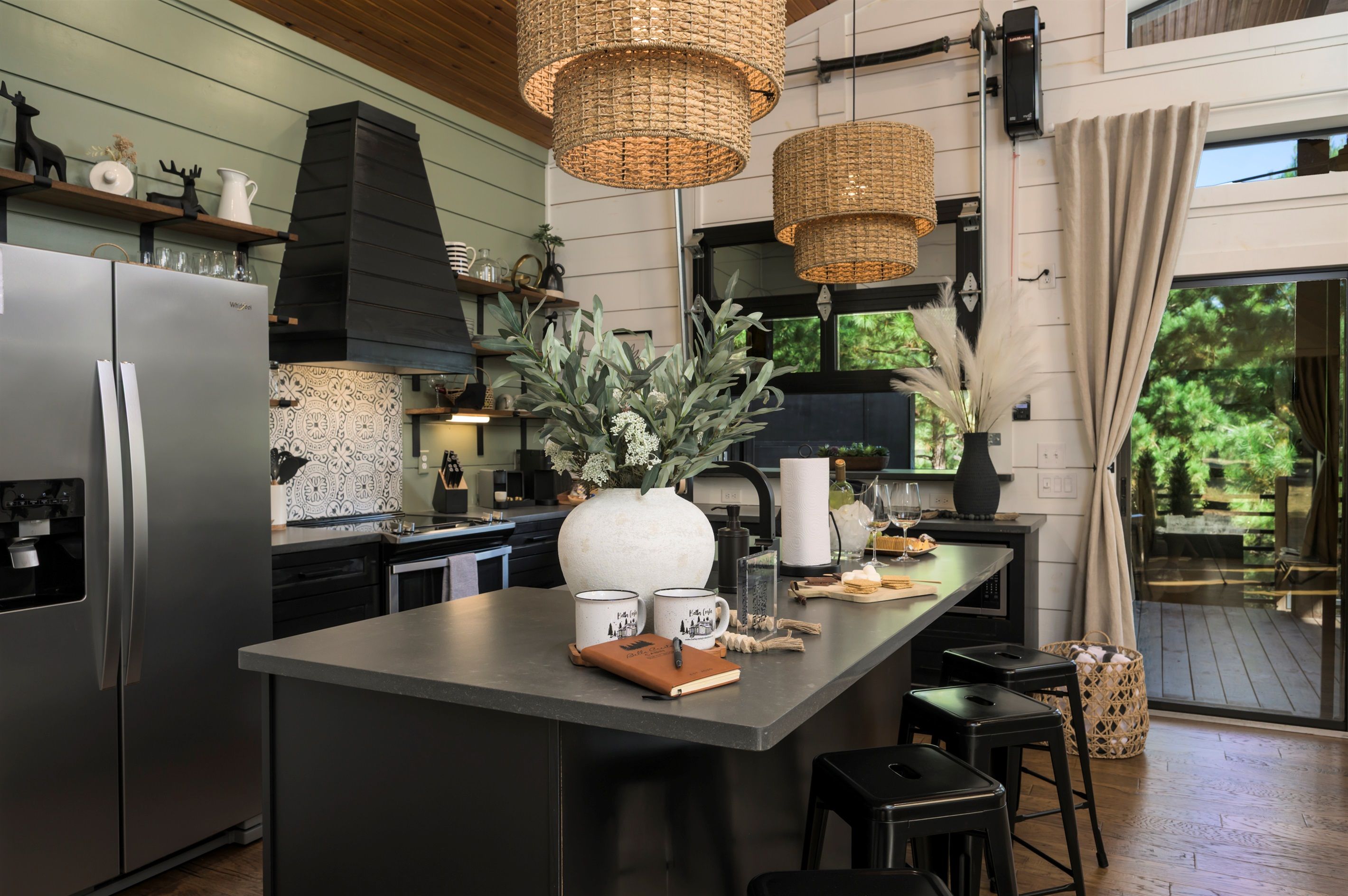 A modern kitchen with a central island, stainless steel appliances, and wicker pendant lights.