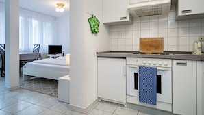 Une cuisine moderne avec des armoires blanches, une cuisinière et un four à micro-ondes. On peut voir une planche à découper en bois sur le comptoir.