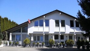 Un bâtiment blanc avec un toit en pente, de nombreuses fenêtres et une antenne parabolique.