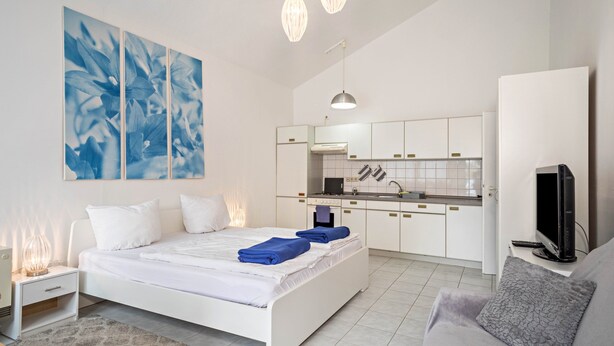 Ein modernes Schlafzimmer mit Bett, Nachttisch und Fernseher.
