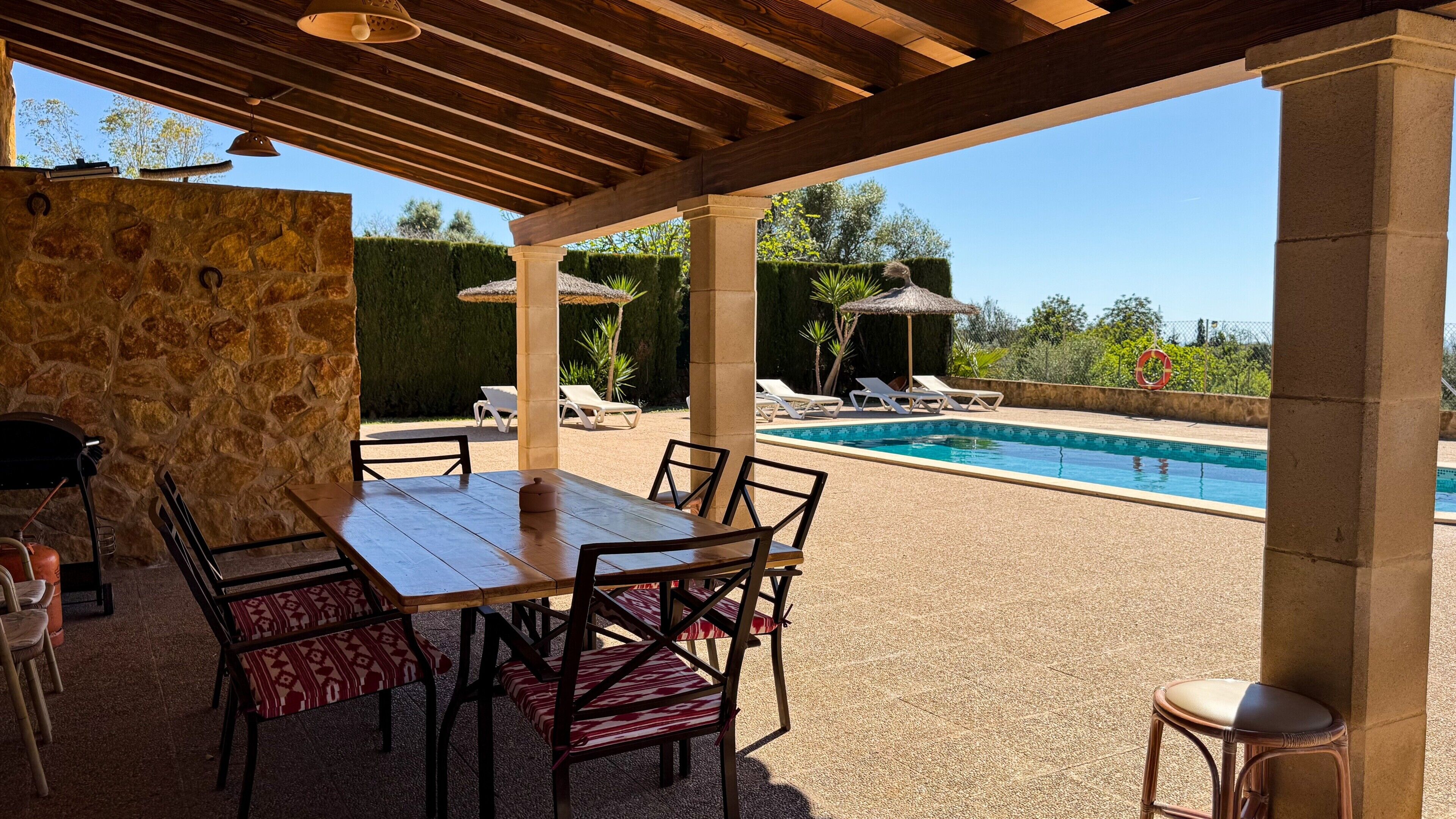 Un patio al aire libre con piscina, muros de piedra y sillones de descanso.