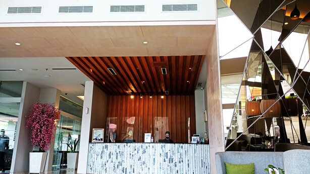 A modern lobby with a geometric ceiling design, a reception desk, and a seating area with a green cushion. - The MELIO Enim (Muara Enim)