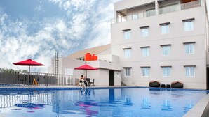 A swimming pool with a clear blue water surface, surrounded by a modern building with multiple windows and balconies. - The MELIO Enim (Muara Enim)