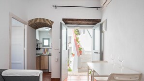 A compact living space with a dining area, a kitchen, and a staircase leading to an outdoor area.