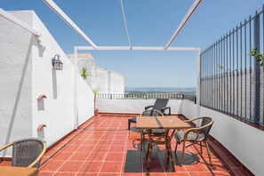 Una terraza con una mesa y sillas, una planta en maceta y vistas del paisaje.