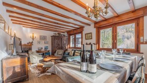 Ein Essbereich mit Holzbalkendecke, einem Kronleuchter, einem gedeckten Tisch und Blick auf Bäume.