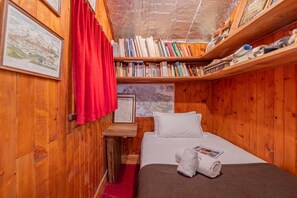 Une pièce en bois avec un lit, une étagère remplie de livres et un rideau rouge.