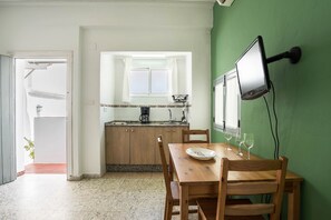 A kitchen with a window, a dining table with chairs, and a wall-mounted TV.