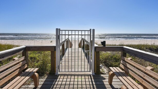 A wooden boardwalk leading to a beach with a gate and benches. - Villa A2, Beach front, ground level! (Eastpoint)