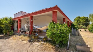 Une maison à l’extérieur rouge, avec un porche abrité et un hamac.
