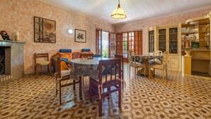 Un espace repas avec un sol à motifs, des chaises en bois, une table ronde et un luminaire suspendu.